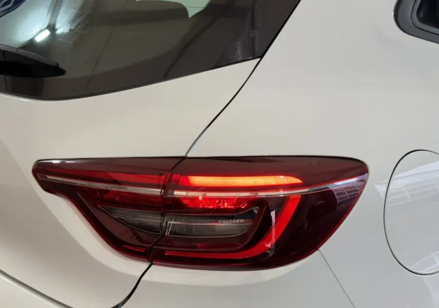 Gros plan sur le feu arrière droit rouge de la Renault Clio Business blanche, avec la trappe à carburant visible.