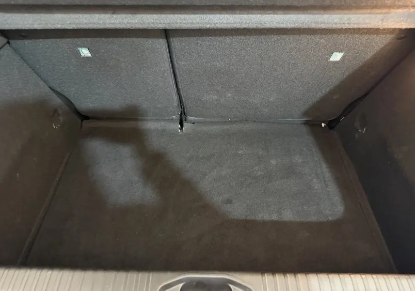 Vue plongeante sur le coffre noir de la Renault Clio Business blanche, montrant l’espace de rangement arrière.