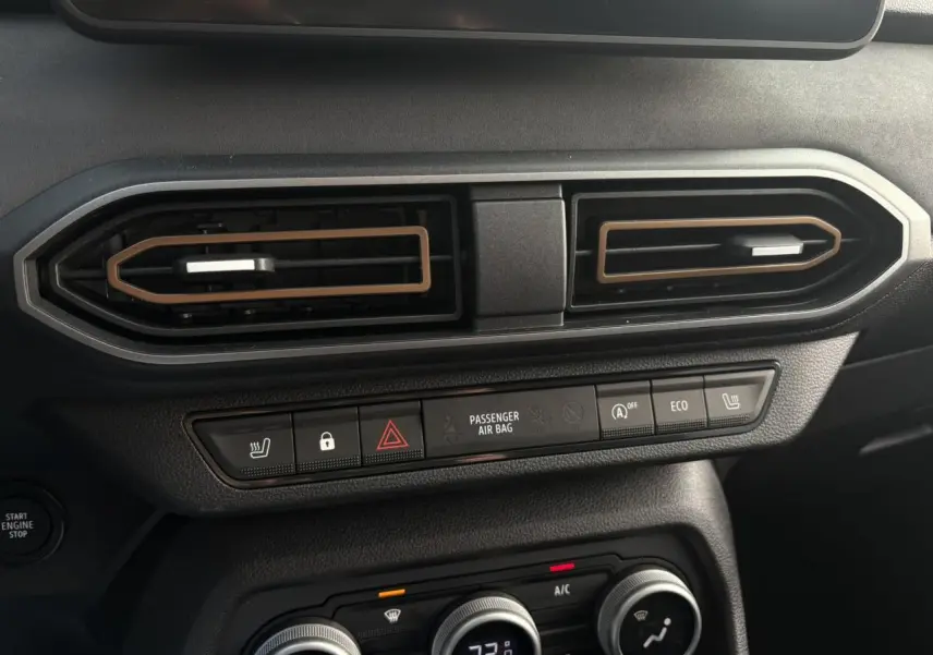 Détail du tableau de bord du Dacia Jogger gris urbain, avec commandes de climatisation et boutons fonctionnels visibles.