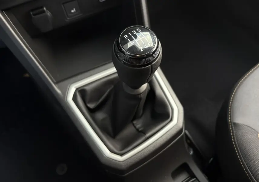 Le levier de vitesses manuel noir de la Dacia Jogger 2024 vu en gros plan depuis l'intérieur côté conducteur.