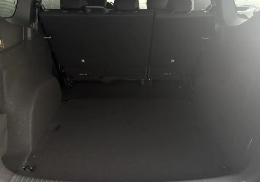 Coffre spacieux du Dacia Jogger Gris Urbain vu de l'arrière avec sièges arrière relevés et intérieur sombre.