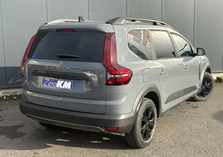 Vue 3/4 arrière droite du Dacia Jogger Gris Urbain avec jantes noires et barres de toit modulaires.