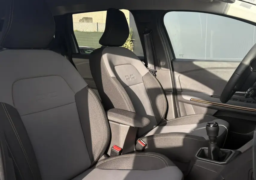 Vue intérieure côté droit des sièges avant gris clair et foncé du Dacia Jogger ECO-G 100 Extreme+ avec accoudoir et levier de vitesse manuel.
