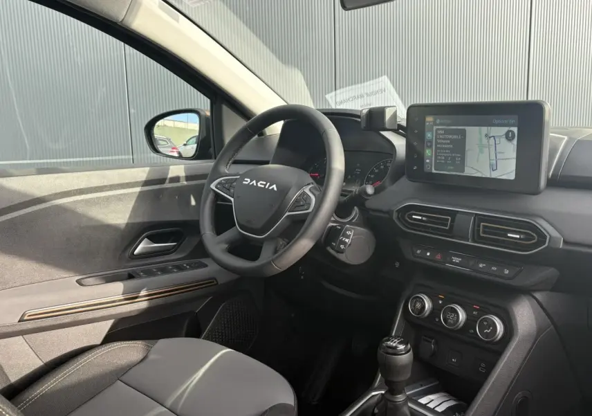 Intérieur côté conducteur du Dacia Jogger 2024 avec volant, écran tactile GPS et levier de vitesse manuel visibles.