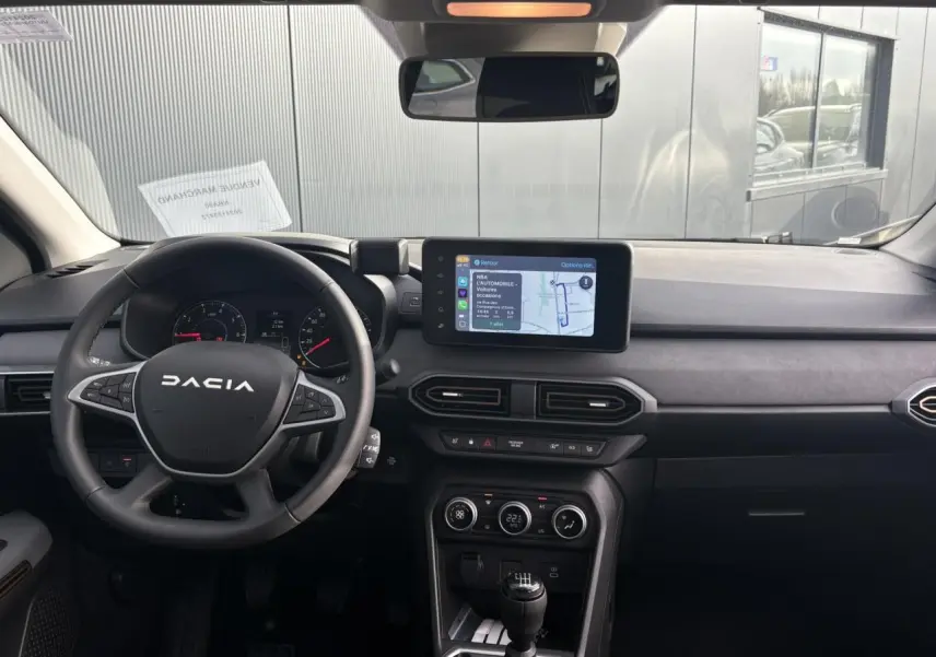 Vue intérieure frontale du tableau de bord du Dacia Jogger 2024 avec écran tactile GPS et volant multifonction noir.