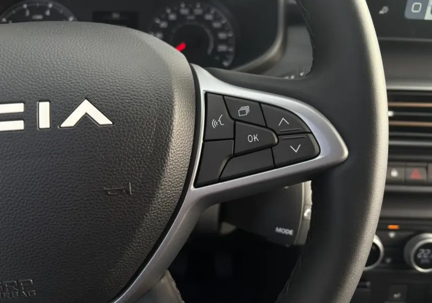 Gros plan sur le volant de la Dacia Jogger 2024, montrant les commandes multifonctions côté droit en plastique noir et argent.