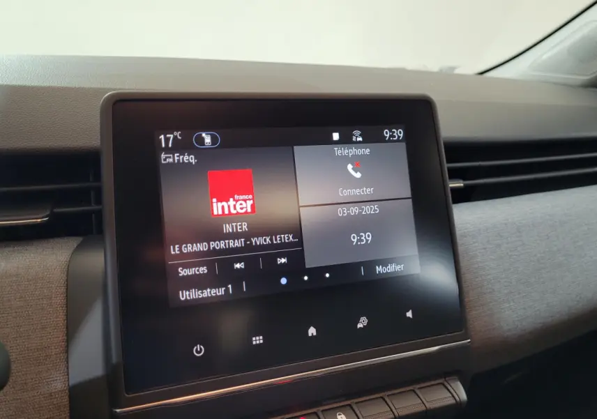 Écran tactile central affichant la radio et téléphone dans l'habitacle d'une Renault Clio bleu 2025.