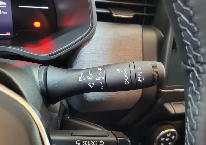 Gros plan sur la manette d'essuie-glace à gauche du volant d'une Renault Clio bleu 2025, intérieur moderne.