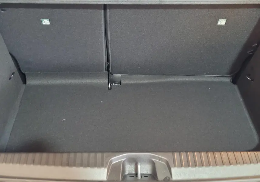 Coffre ouvert et vide de la Renault Clio bleu, montrant la banquette arrière rabattue et le revêtement intérieur noir.