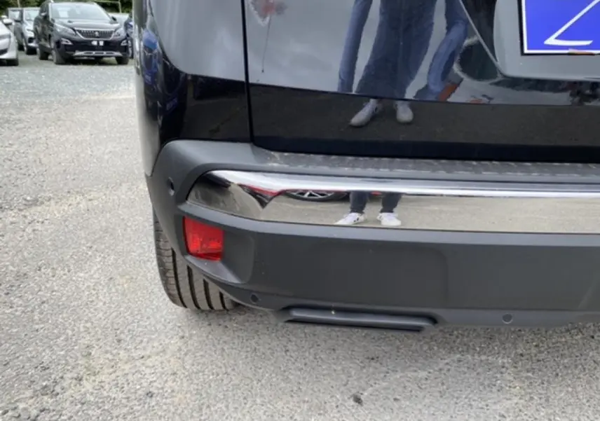 Gros plan sur le pare-chocs arrière noir perla nera du Peugeot 3008 2021, avec feu antibrouillard et capteurs de recul visibles.