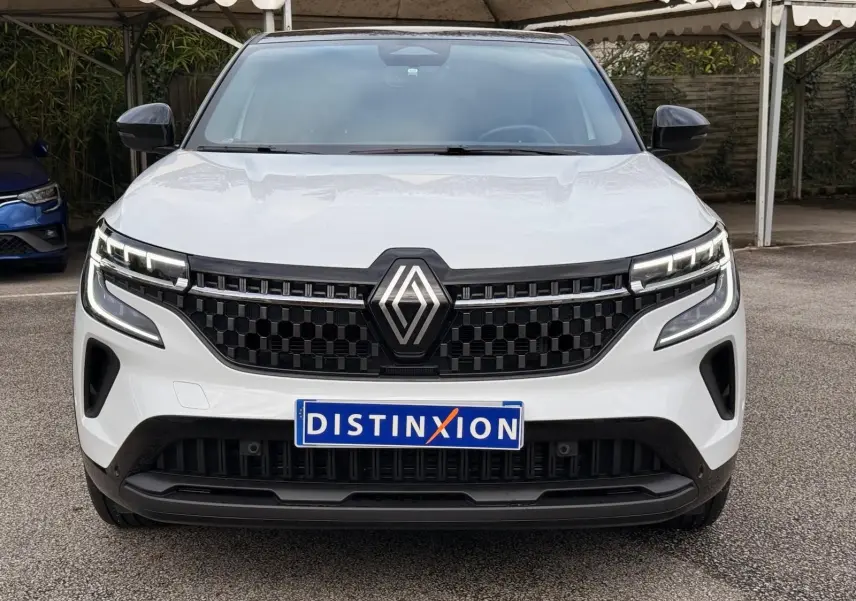 Vue frontale d'un Renault Austral 2023 blanc nacré avec toit noir, calandre noire à motif hexagonal et phares LED distinctifs.