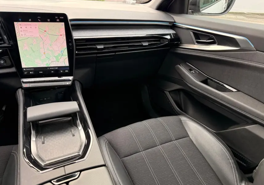 Vue intérieure côté passager du tableau de bord et console centrale du Renault Austral E-Tech 200 blanc nacré avec écran tactile et sellerie noire.