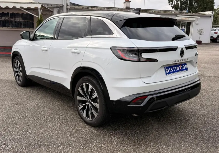 Vue arrière côté gauche du Renault Austral blanc nacré avec toit noir et jantes alliage, stationné sur un parking extérieur.