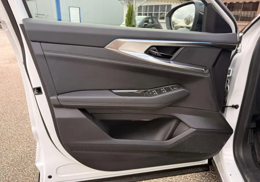 Intérieur côté gauche de la porte avant d'une Renault Austral 2023 blanc nacré avec garniture noire et commandes électriques.