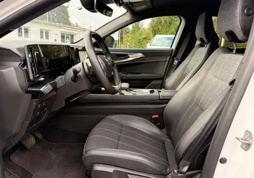 Vue intérieure côté conducteur du Renault Austral E-Tech 200 blanc nacré, sièges tissu et cuir noir avec tableau de bord moderne.