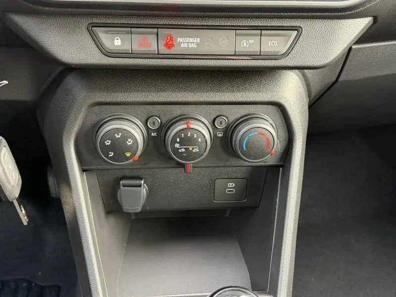 Vue rapprochée du tableau de bord central de la Dacia Sandero 2025, montrant les commandes de climatisation et les voyants de sécurité.