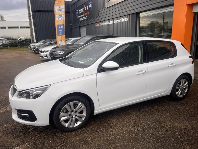 Peugeot 308 blanc banquise vue de côté droit en extérieur, avec jantes alu et vitres teintées.