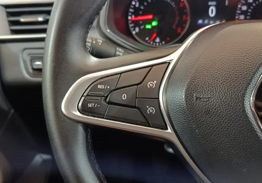 Gros plan sur le volant cuir synthétique noir de la Renault Clio 2023, avec commandes multifonctions côté gauche.