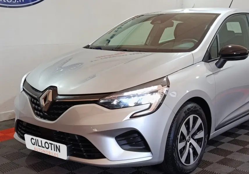 Vue 3/4 avant droite d’une Renault Clio gris clair 2023 avec phares LED et jantes distinctives.