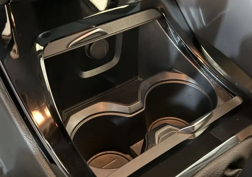 Gros plan sur les porte-gobelets noirs et la console centrale brillante de la BMW X2 sDrive18i Lounge 2023.