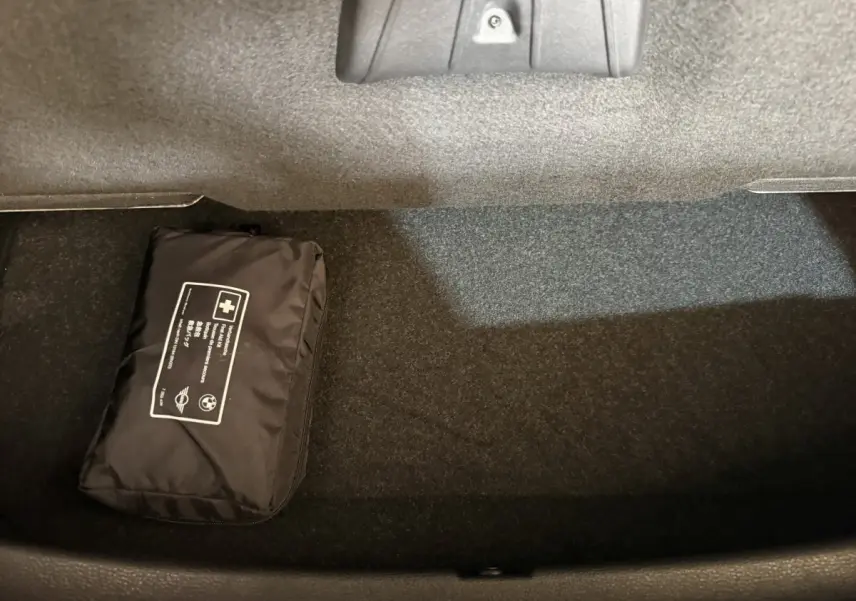 Gros plan sur le coffre noir intérieur d’une BMW X2 sDrive18i Lounge 2023 avec trousse de secours noire posée.