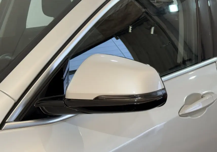 Gros plan sur le rétroviseur côté gauche blanc du BMW X2 sDrive18i Lounge 2023 avec poignée de porte assortie.