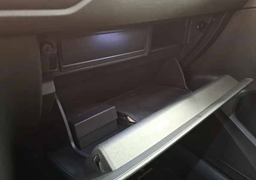 Gros plan sur la boîte à gants ouverte du CUPRA Ateca 2024, avec accessoires noirs à l’intérieur, vue côté passager.