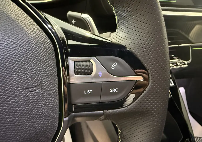 Gros plan sur les commandes gauche du volant en cuir perforé du Peugeot 2008 GT 2025, intérieur noir.