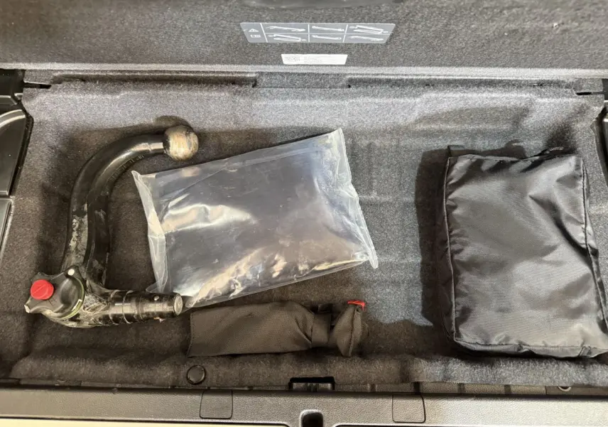 Coffre ouvert d’une BMW Série 5 Touring 520d noir, montrant le rangement sous plancher avec attelage amovible et accessoires.