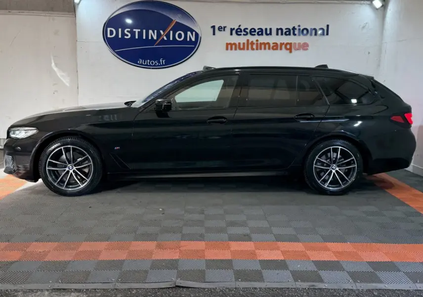 BMW Série 5 Touring 520d M Sport noire vue de profil côté gauche, avec jantes alliage et toit noir brillant.