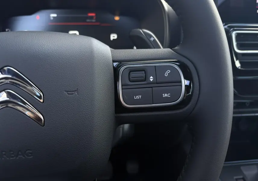 Gros plan sur le volant cuir noir du Citroën C5 Aircross 2026 avec commandes intégrées et logo chromé.