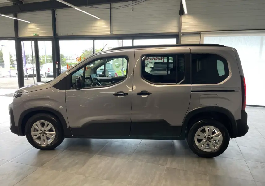 Vue de profil côté gauche du Peugeot Rifter gris Artense avec portes coulissantes et jantes tôles 16 pouces en showroom.