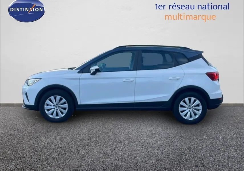 Vue latérale droite d'un SEAT Arona blanc avec toit gris, posé sur sol bitumé devant un mur clair.