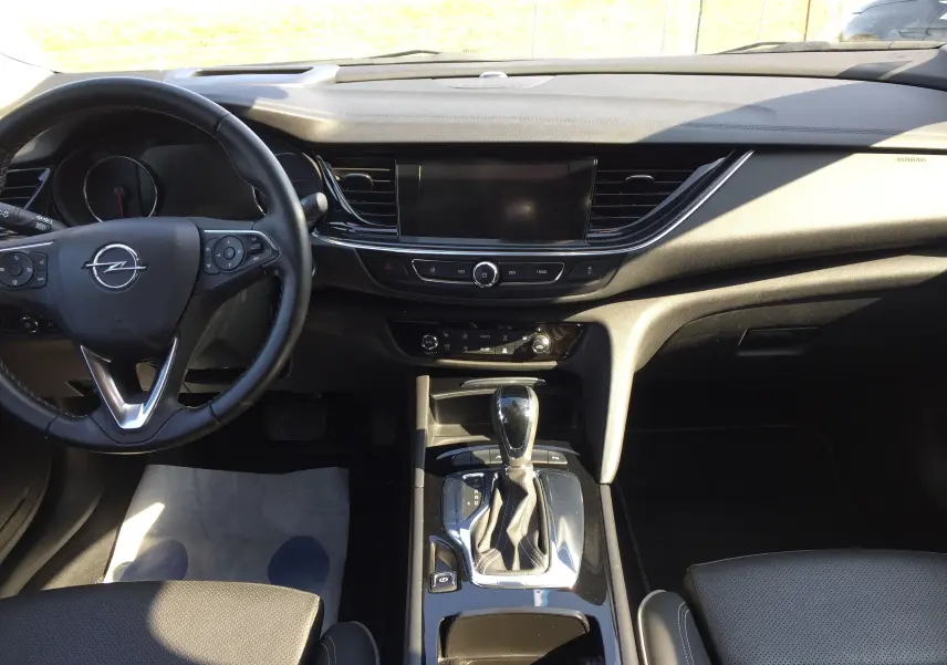 Intérieur noir de l'Opel Insignia Grand Sport 2017, vue de face sur le tableau de bord et la console centrale avec boîte auto.