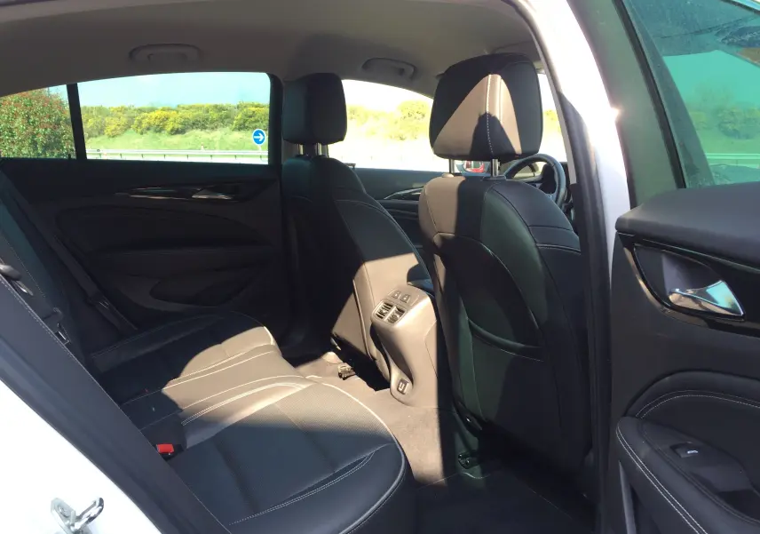 Vue intérieure côté droit arrière d'une Opel Insignia Grand Sport blanc nacré, sièges cuir noirs et finitions modernes.