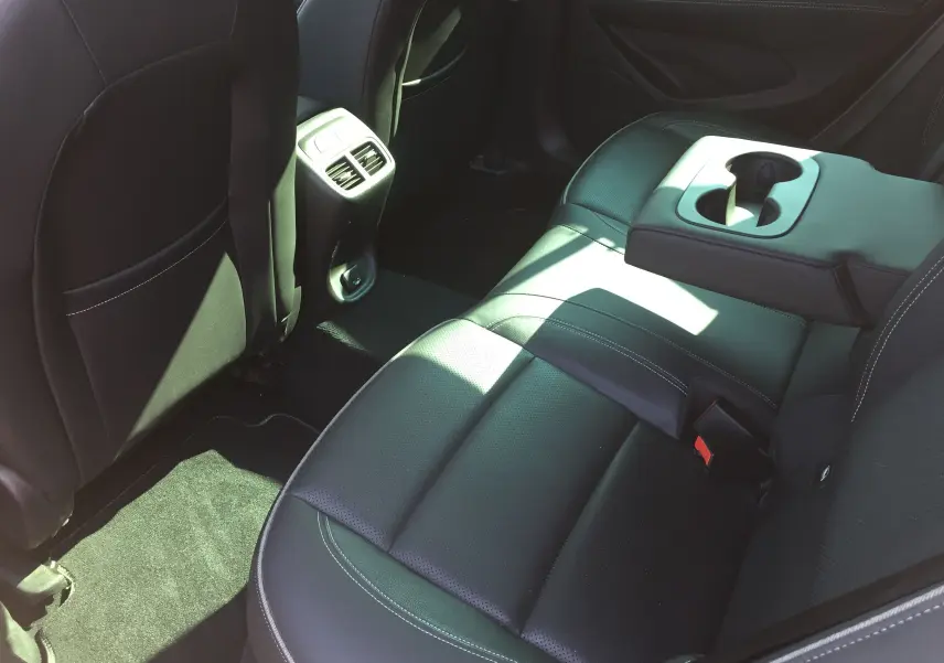 Vue intérieure arrière côté droit de l'Opel Insignia Grand Sport 2017, sièges cuir noir avec accoudoir central et porte-gobelets.