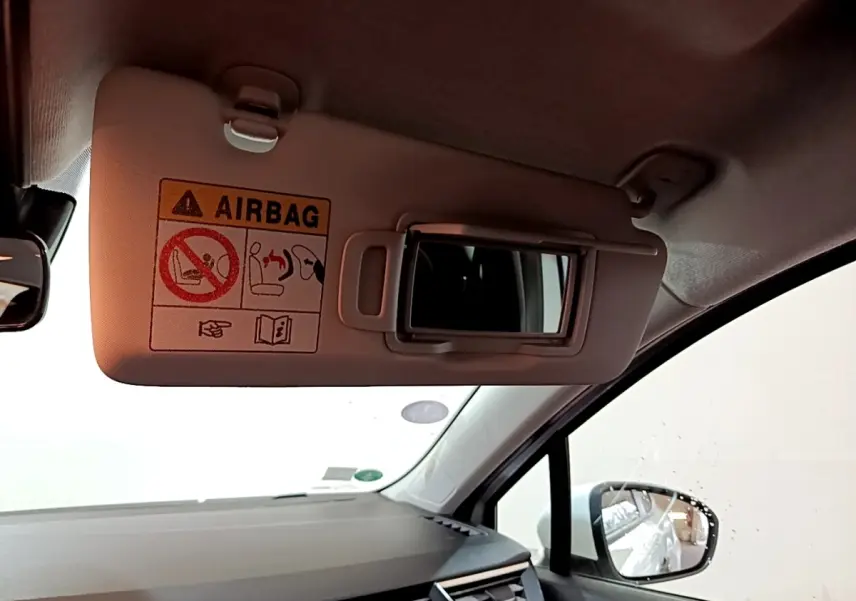 Détail du pare-soleil côté conducteur avec miroir et avertissement airbag dans l'habitacle d'une Renault Clio blanche.
