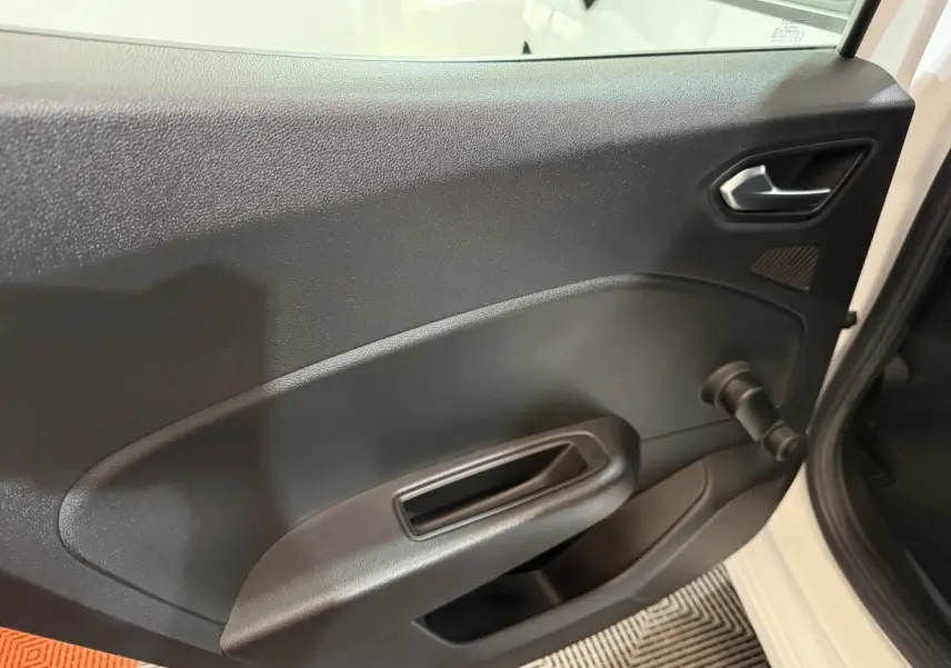 Vue rapprochée de la porte intérieure côté droit d’une Renault Clio Business blanche, avec poignée et manivelle de vitre.