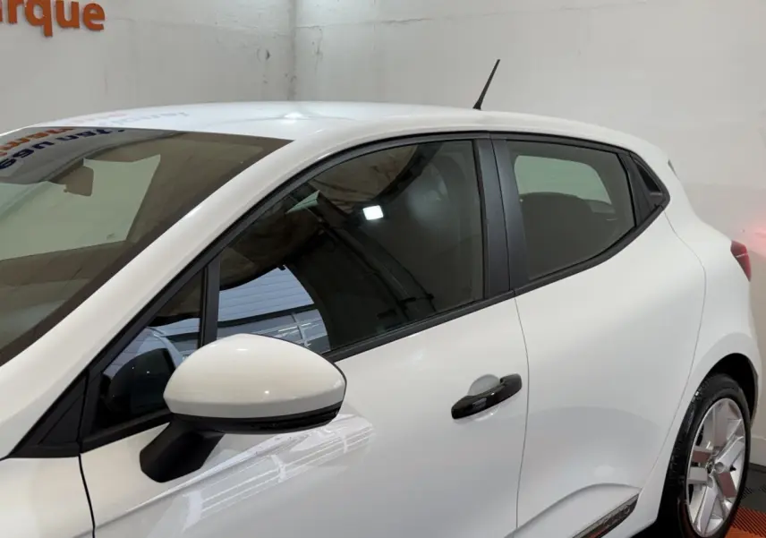 Vue latérale gauche d'une Renault Clio Business SCe 75 blanche, avec rétroviseur et poignées noires contrastantes.