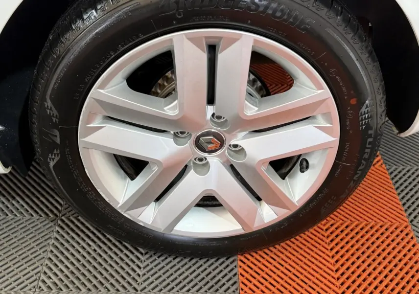 Gros plan sur la roue avant droite d'une Renault Clio Business blanche, jante alliage à cinq branches.