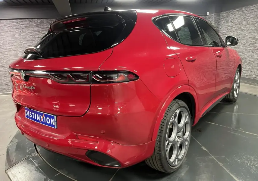 Vue 3/4 arrière droite de l'Alfa Romeo Tonale rouge avec toit noir, jantes 20 pouces et feux arrière full LED.