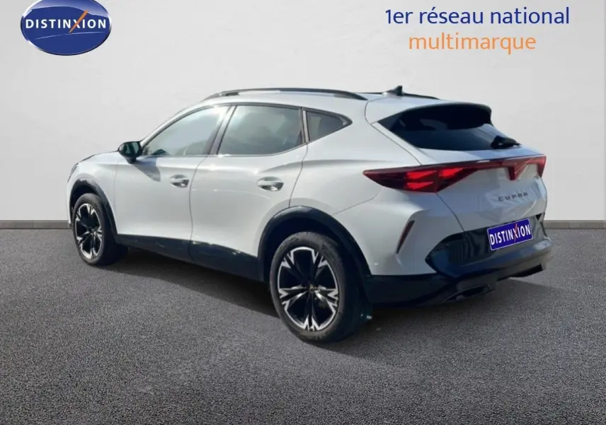 Vue 3/4 arrière droite d'un CUPRA Formentor blanc neige métal avec jantes noires et feux arrière LED distinctifs.