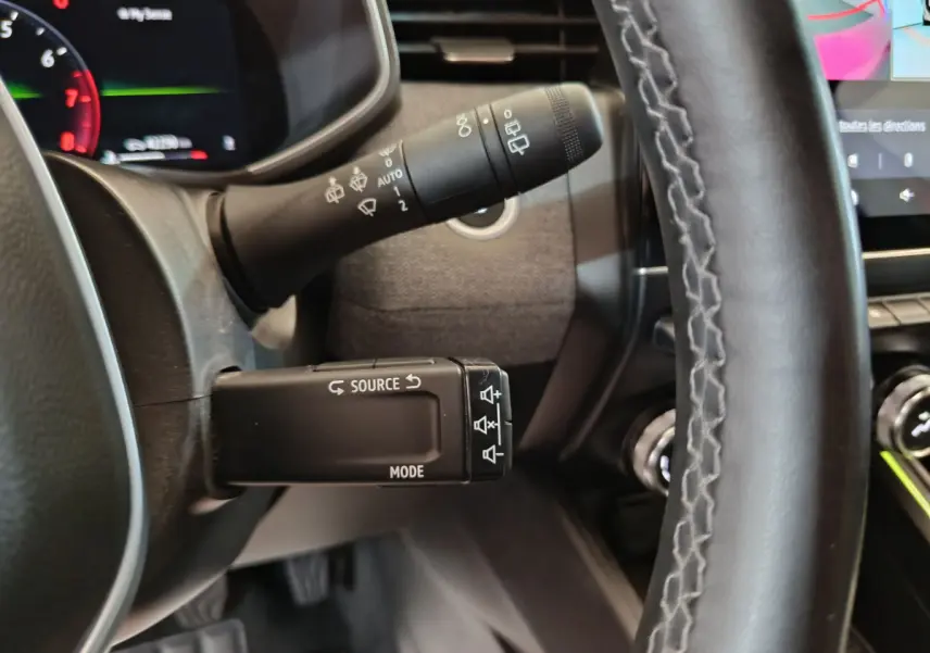 Gros plan sur la commande multifonctions à gauche du volant dans l’habitacle de la Renault Clio Techno TCe 90 rouge 2024.