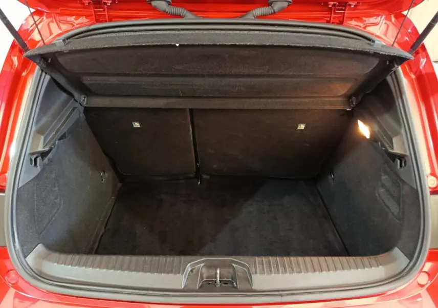 Coffre ouvert vu de l'arrière d'une Renault Clio Techno TCe 90 rouge, montrant l'espace de chargement vide.