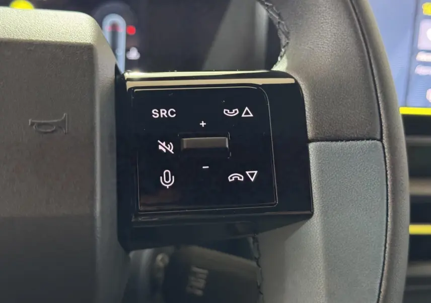 Gros plan sur les commandes gauche du volant cuir de la Fiat Grande Panda 2025, boutons multifonctions noirs.