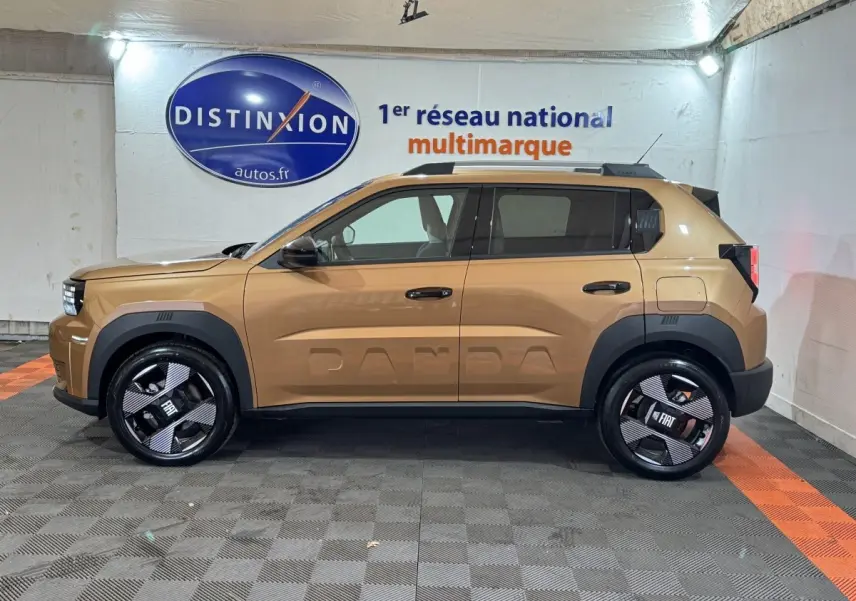 Vue de profil côté gauche d'une FIAT Grande Panda marron avec logo PANDA embossé sur la porte, roues noires distinctives.