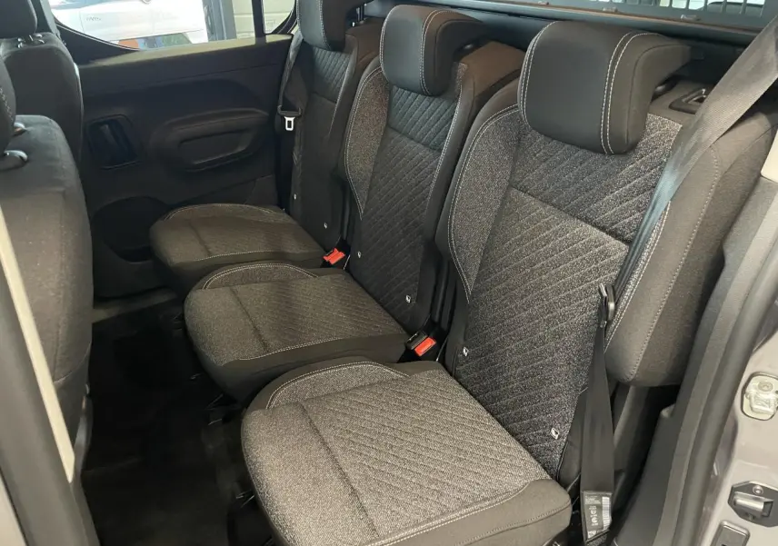 Vue intérieure des sièges arrière en tissu gris du Peugeot Rifter 2026, avec portes latérales coulissantes ouvertes.