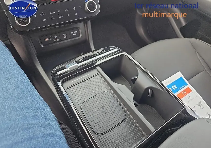 Gros plan sur la console centrale noire du Hyundai Tucson 2025 avec chargeur sans fil et porte-gobelets visibles.