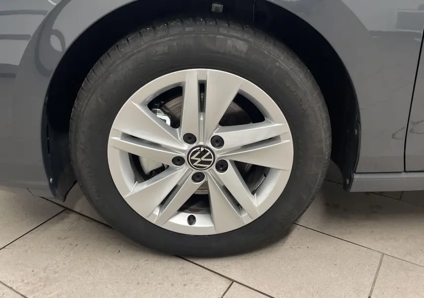 Gros plan sur la roue avant gauche d'une Volkswagen Golf 1.5 TSI gris dauphin avec jante alliage à cinq branches.
