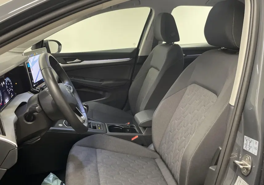 Intérieur avant de la Volkswagen Golf 1.5 TSI 2024 en Gris Dauphin, sièges tissu gris et tableau de bord numérique.